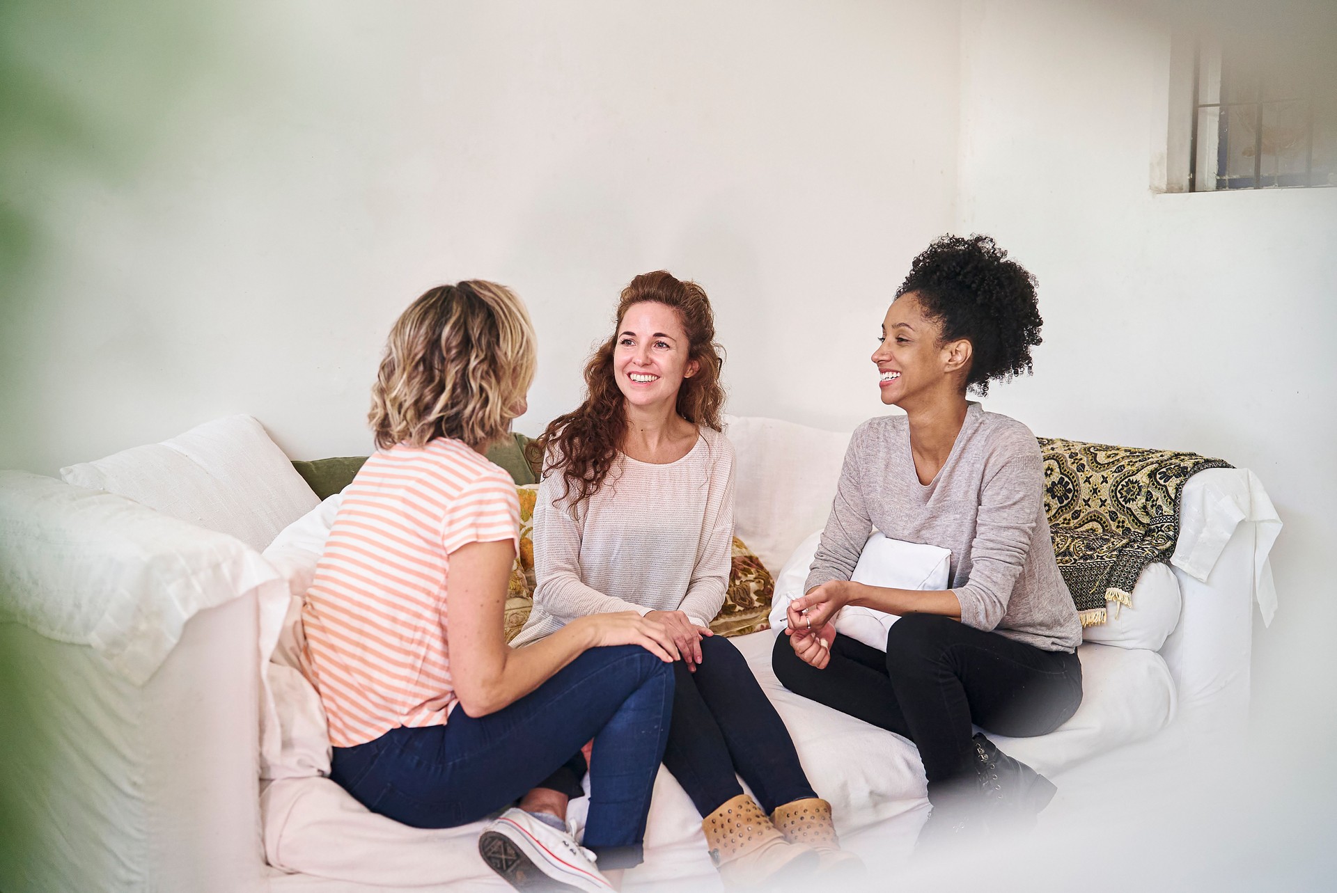 Female friends discussing while sitting on couch