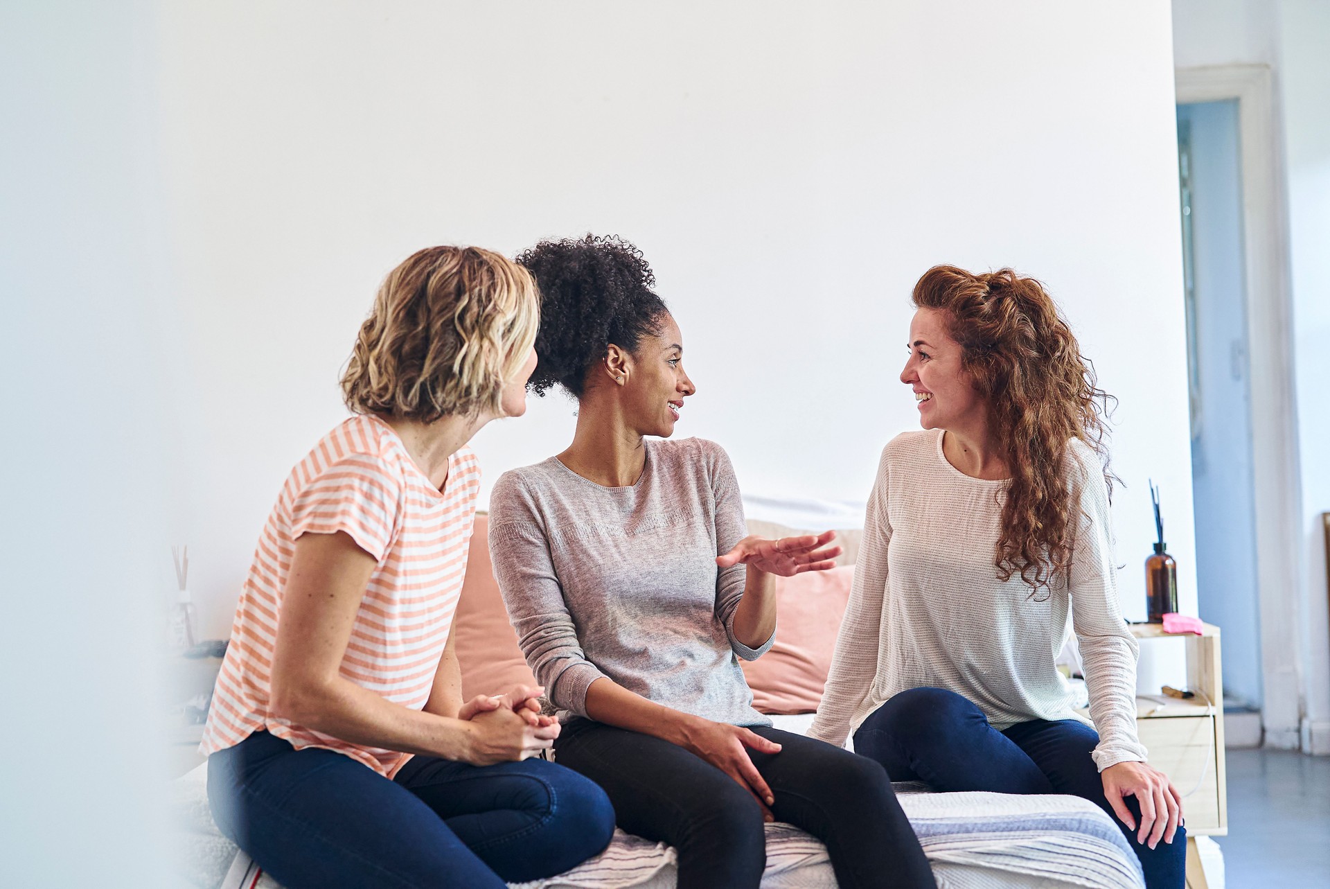 Adult women having conversation while sitting on bed